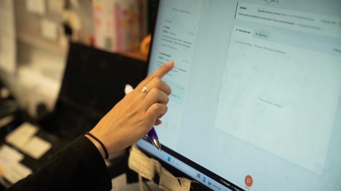 A close view of a hand pointing at a dispensary screen, mid-conversation.